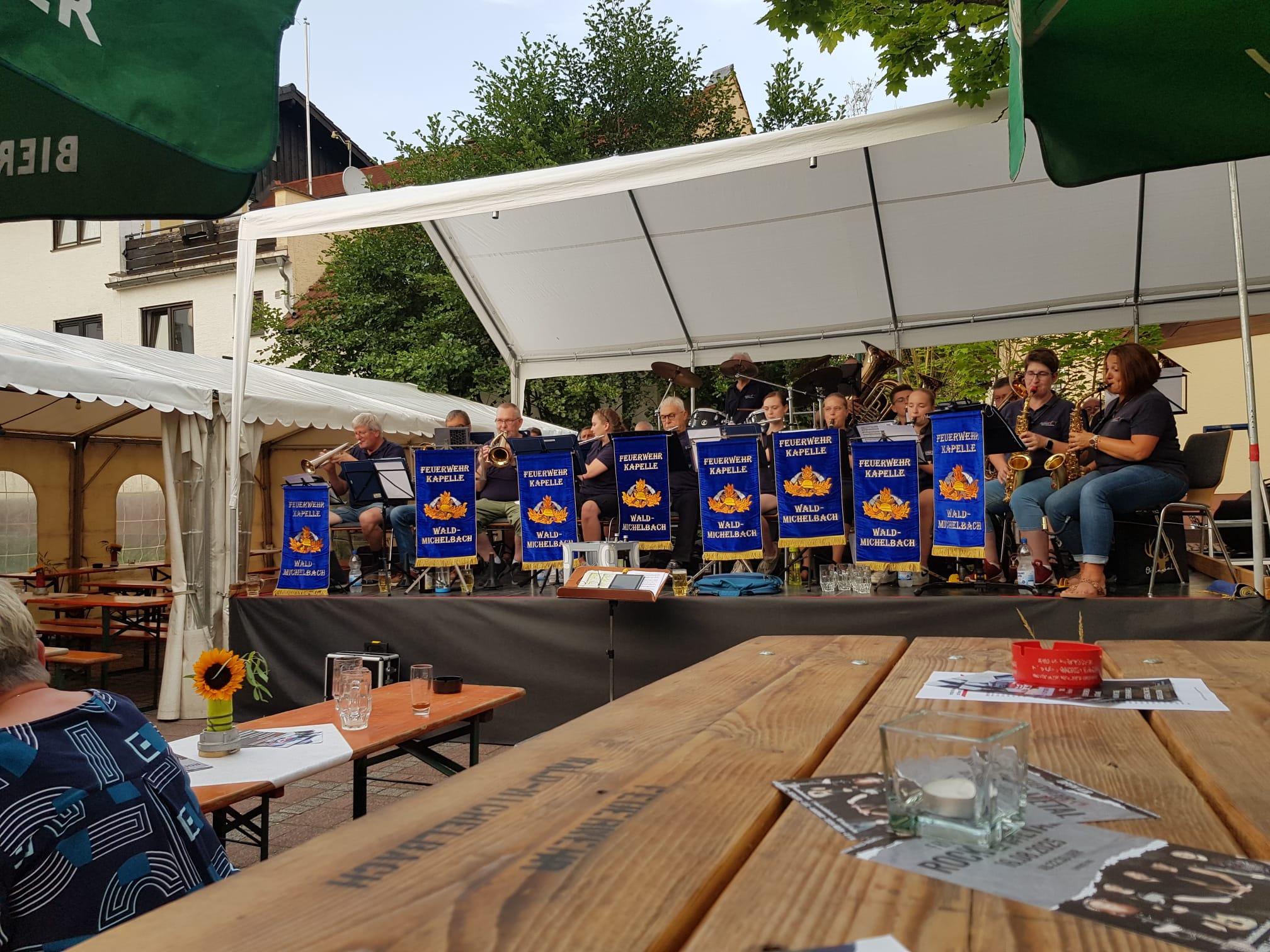 Festzeltauftritt der Kapelle am Abend mit blauen Pultfahnen