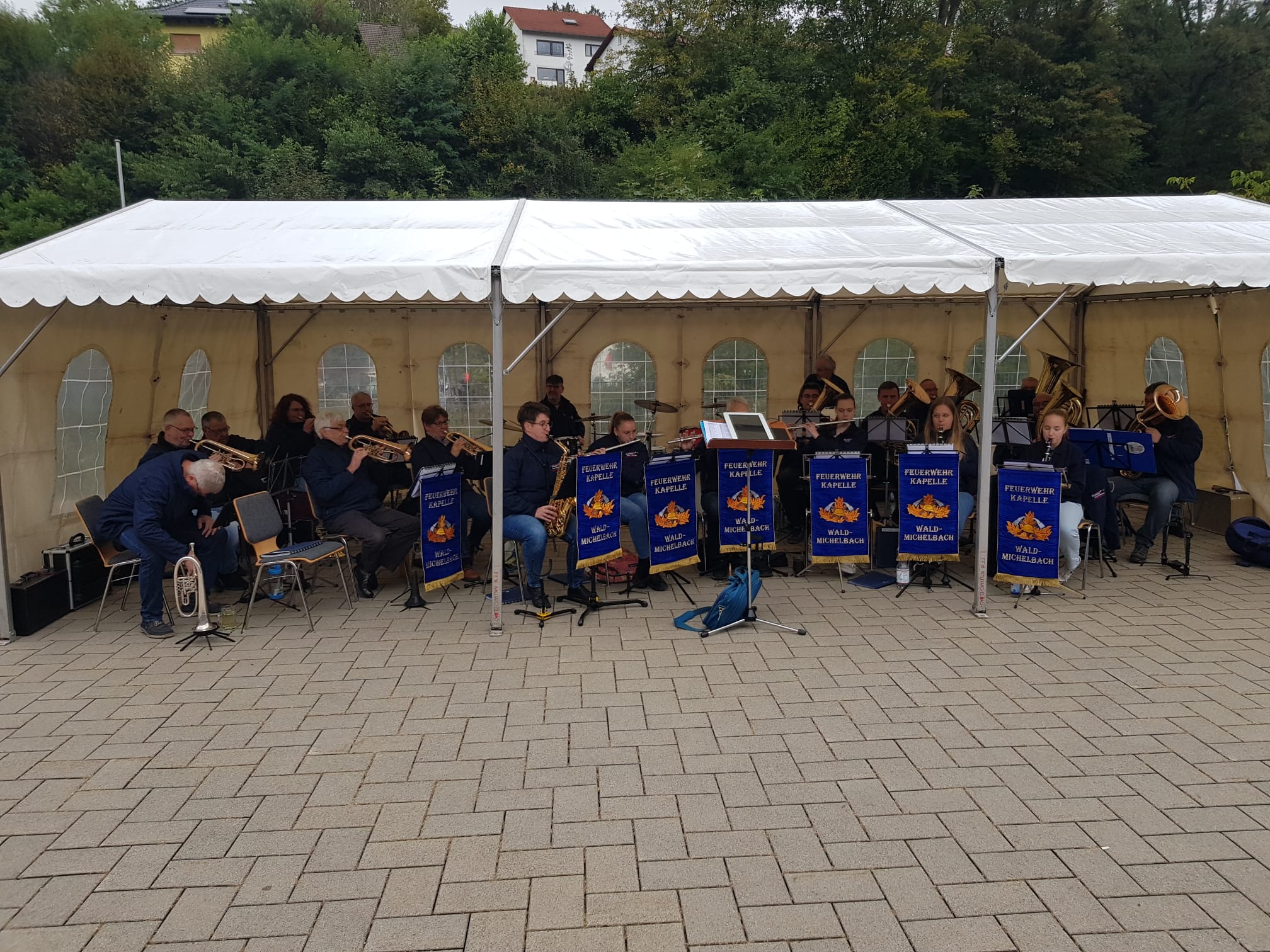 Auftritt unter weißem Zelt mit Biergarnituren davor